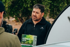 Productor regional de Agro Sustentable sostiene una caja de bioinsumo BIOFERT GTG durante una entrevista sobre agricultura orgánica.