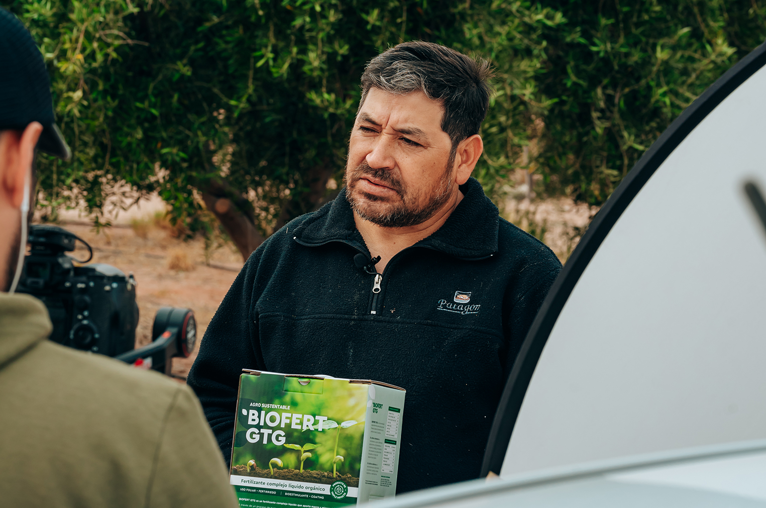 Productor regional de Agro Sustentable sostiene una caja de bioinsumo BIOFERT GTG durante una entrevista sobre agricultura orgánica.