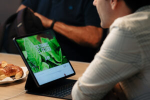 Hombre frente a una laptop con la web de Agro Sustentable, observando la frase "Cultivamos el futuro", en un entorno de reunión profesional.