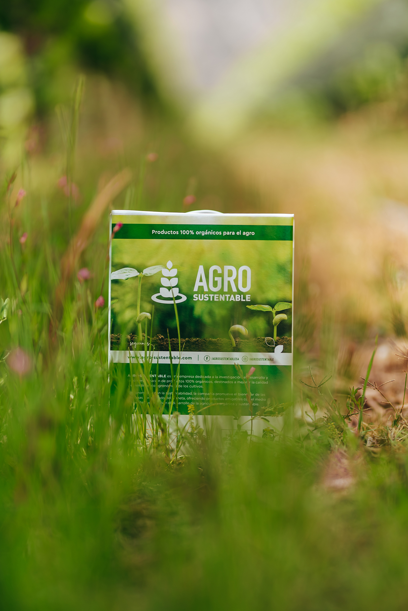 Bolsa de productos orgánicos de Agro Sustentable entre pasto y vegetación natural, destacando su compromiso con el agro ecológico.