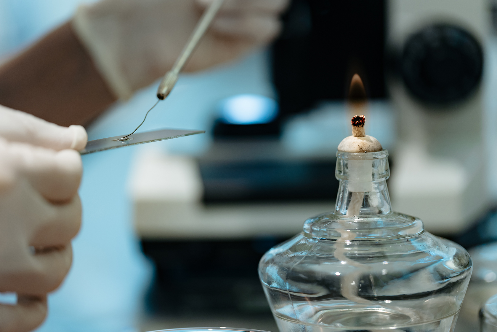 Análisis de laboratorio agrícola con llama de mechero y muestra en portaobjetos, representando procesos de investigación en bioinsumos.