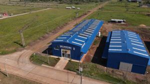 Vista aérea de las instalaciones de Agro Sustentable en Misiones, Argentina, con techos azules equipados con paneles solares rodeados de espacios verdes.