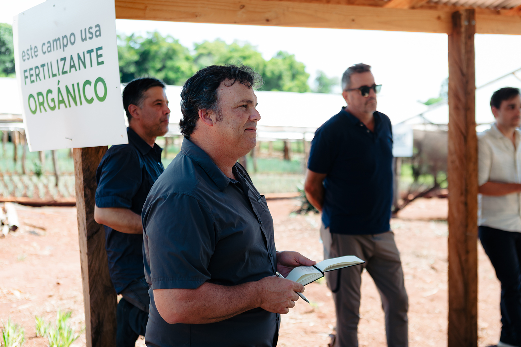 Profesionales discutiendo la certificación orgánica en una finca que utiliza fertilizantes orgánicos, con un enfoque en los beneficios de este sistema para la producción agrícola sostenible y la exportación.