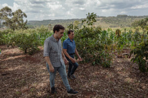 Matías Imperiale y un productor agropecuario caminan entre cultivos sostenibles en un predio rural rodeado de vegetación en Misiones.